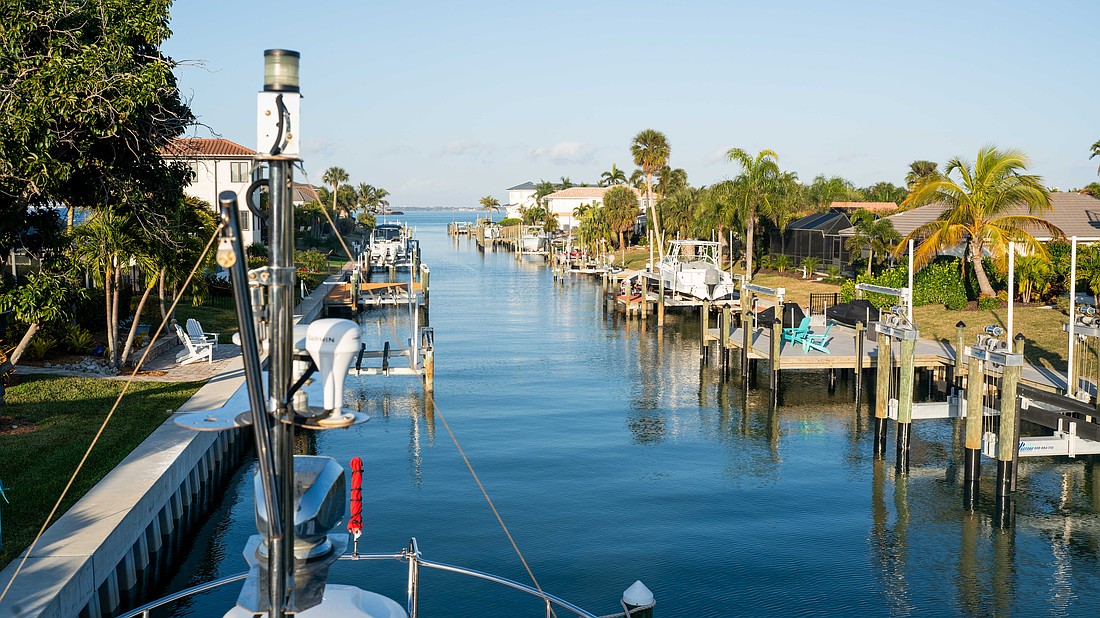 Boat lifts flank each side of the canal in a Country Club Shores neighborhood. The town of Longboat Key is preparing to enact a continuous canal maintenance program that would include flat fees and ad-valorem assessments for residents.