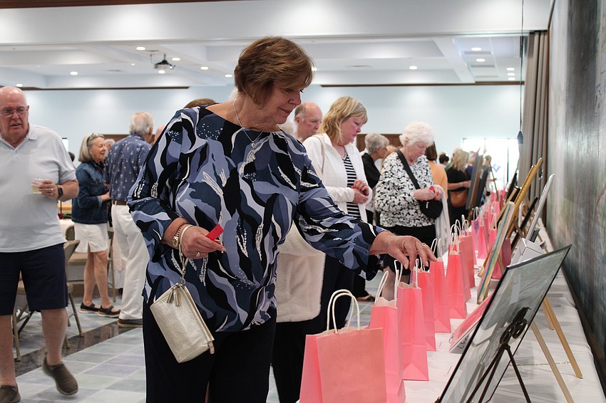 Fran Zinna puts in a raffle ticket for one of her top picks of pieces of art being displayed at the Women's Guild Valentine's Day art show at St. Mary, Star of the Sea, Catholic Church.