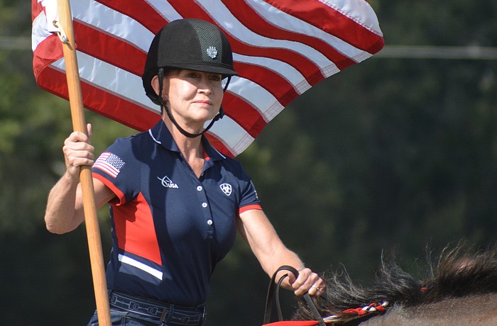Misdee Miller, the new owner of the Sarasota Polo Club with her husband, James, presents the colors during the National Anthem Dec. 2 on opening day.