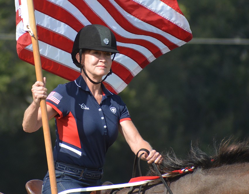 Misdee Miller, the new owner of the Sarasota Polo Club with her husband, James, presents the colors during the National Anthem Dec. 2 on opening day.