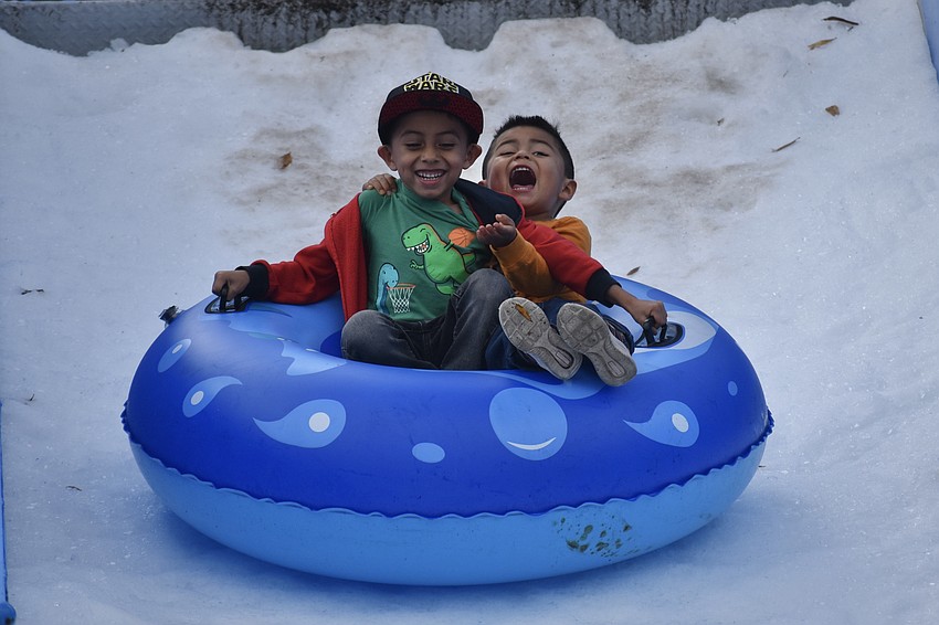 Kindergartener Gustavo Machuca Salazar and preschooler Julian Machuca Salazar head down the slide.