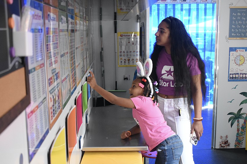 Kindergartener Amiyla Muhammad and her mother Ebony Muhammad check out the posters in the Sarasota Police Department's Sarasota Learning Center.