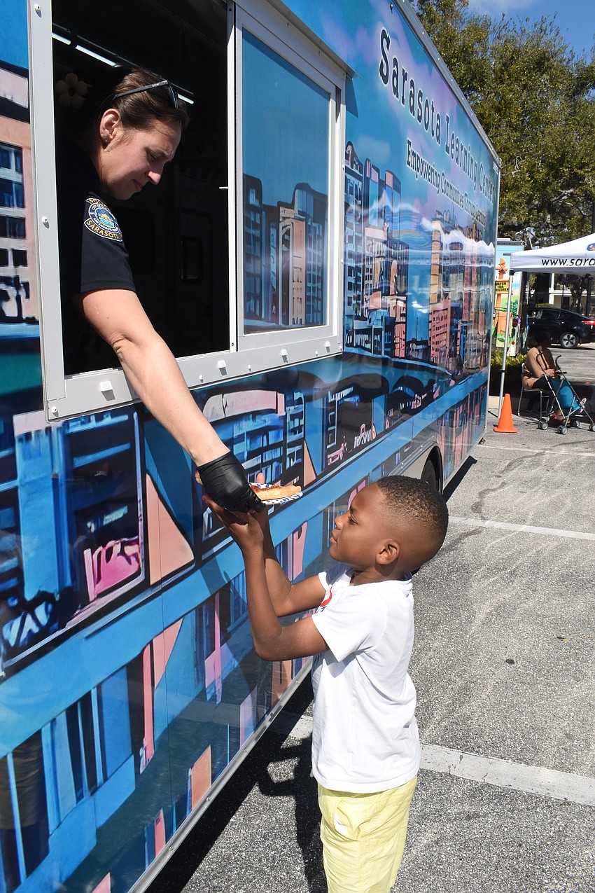 Officer Ashley Griffin hands pizza to first grader Tristan Jackson.