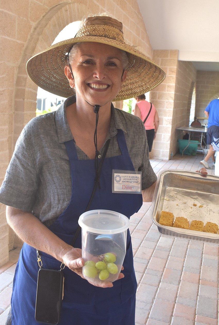 Dina Hobson, a past president and member of St. Barbara Greek Orthodox Church, hands out grapes and Ravani, a cake from northern Greece.