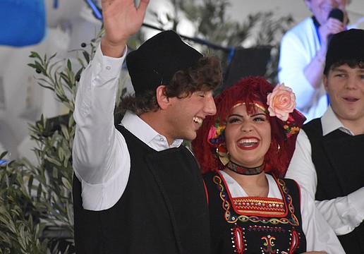 St. Barbara's Hellenic Folk Dance Group member Harrison Barakos gives a wave, while being cheered on by fellow dancers Maria Stylianoudakis and Gianni Cappelluti, as his name is called at the St. Barbara 42nd annual Greek Festival.