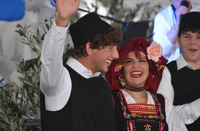 St. Barbara's Hellenic Folk Dance Group member Harrison Barakos gives a wave, while being cheered on by fellow dancers Maria Stylianoudakis and Gianni Cappelluti, as his name is called at the St. Barbara 42nd annual Greek Festival.