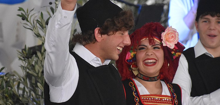 St. Barbara's Hellenic Folk Dance Group member Harrison Barakos gives a wave, while being cheered on by fellow dancers Maria Stylianoudakis and Gianni Cappelluti, as his name is called at the St. Barbara 42nd annual Greek Festival.