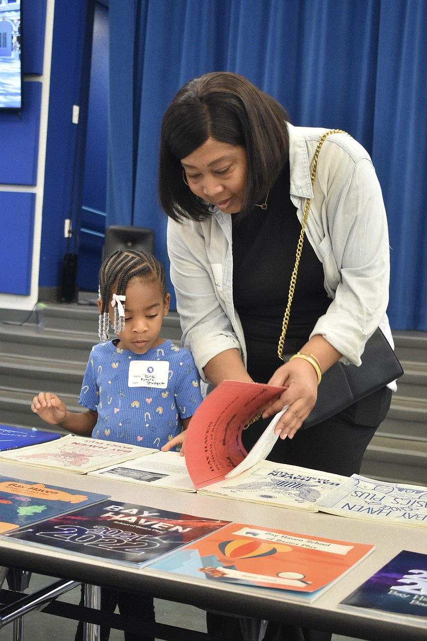 Yara Austin, 5, who will be attending the school next year, looks at a yearbook with her mother Ariel Brown, who was a member of the class of 1995.
