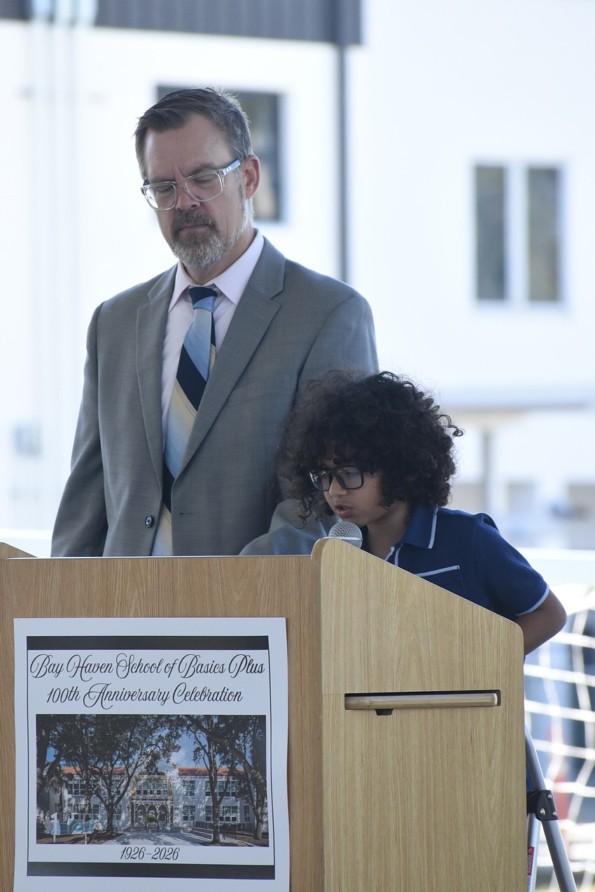 Principal Chad Erickson stands beside third grader Petronius Boles as he reads his essay.