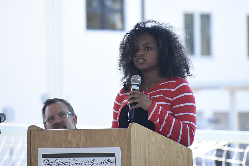 Principal Chad Erickson listens as former student Chloe Truewell of Booker High School offers a speech.