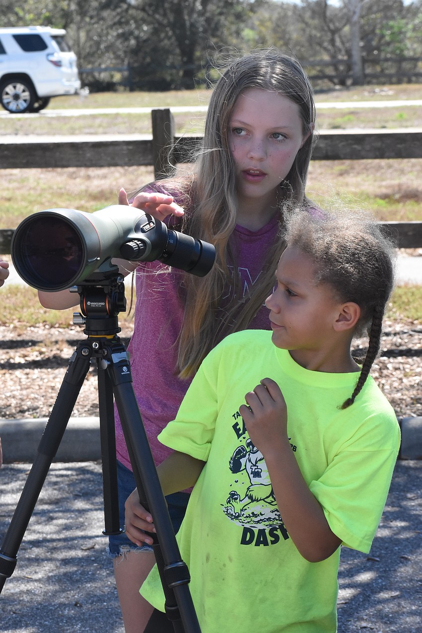 Ahmya Clemons, 13, and her sister McKenna Clemons, 8, use a spotting scope.
