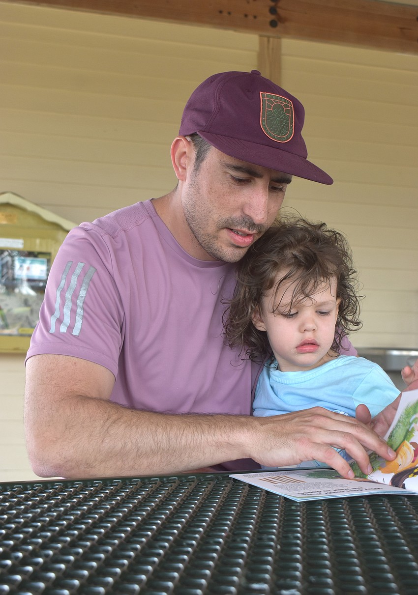 Greg Losi, who is visiting from Buffalo, New York, said the Little Free Libraries are a great resource for kids playing at parks and couldn't wait to read to his 2-year-old daughter Genevieve.