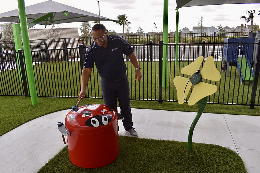 Owner Sanddy Marchena bangs a ladybug drum on the playground.