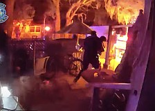 A body-worn camera image shows a Sarasota police officer carrying a female victim from the burning home on North Osprey Avenue.