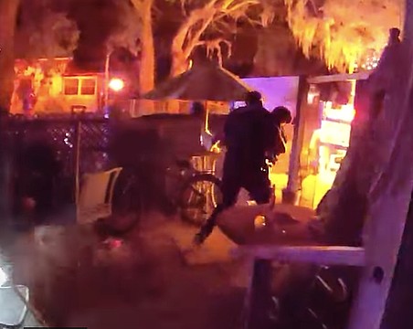 A body-worn camera image shows a Sarasota police officer carrying a female victim from the burning home on North Osprey Avenue.