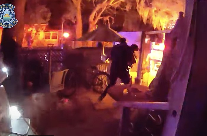 A body-worn camera image shows a Sarasota police officer carrying a female victim from the burning home on North Osprey Avenue.