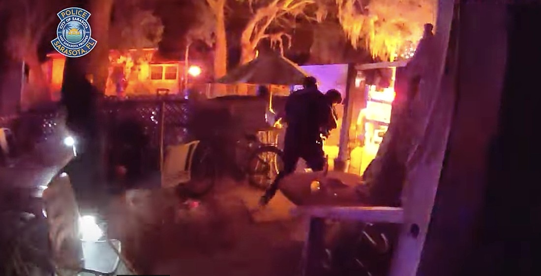 A body-worn camera image shows a Sarasota police officer carrying a female victim from the burning home on North Osprey Avenue.