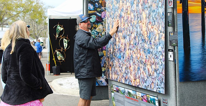 Gary Love of Gary Love Photography shows an art festival-goer how the various places the light hits the shell-covered beach give the up-close image depth. He was one of several new artists featured at the Feb. 21-22 art festival on Longboat Key.