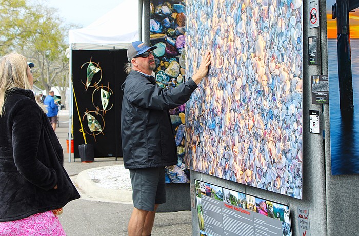 Gary Love of Gary Love Photography shows an art festival-goer how the various places the light hits the shell-covered beach give the up-close image depth. He was one of several new artists featured at the Feb. 21-22 art festival on Longboat Key.