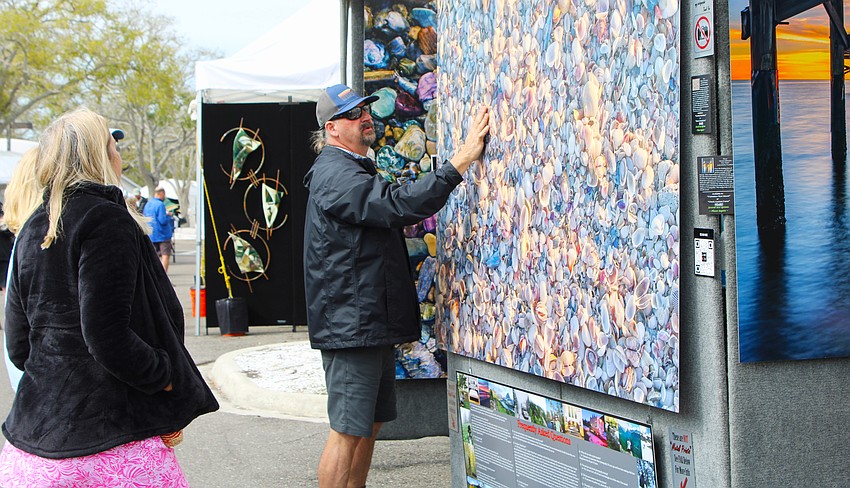 Gary Love of Gary Love Photography shows an art festival-goer how the various places the light hits the shell-covered beach give the up-close image depth. He was one of several new artists featured at the Feb. 21-22 art festival on Longboat Key.