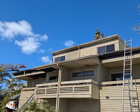 Firefighters break a hole in the roof of a building minutes after first responders extinguished the flames that engulfed a three-story residence devastated by what is reported as a potential electrical fire Monday, Feb. 23.