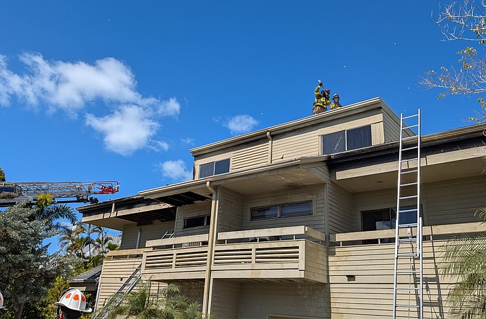 Firefighters break a hole in the roof of a building minutes after first responders extinguished the flames that engulfed a three-story residence devastated by what is reported as a potential electrical fire Monday, Feb. 23.