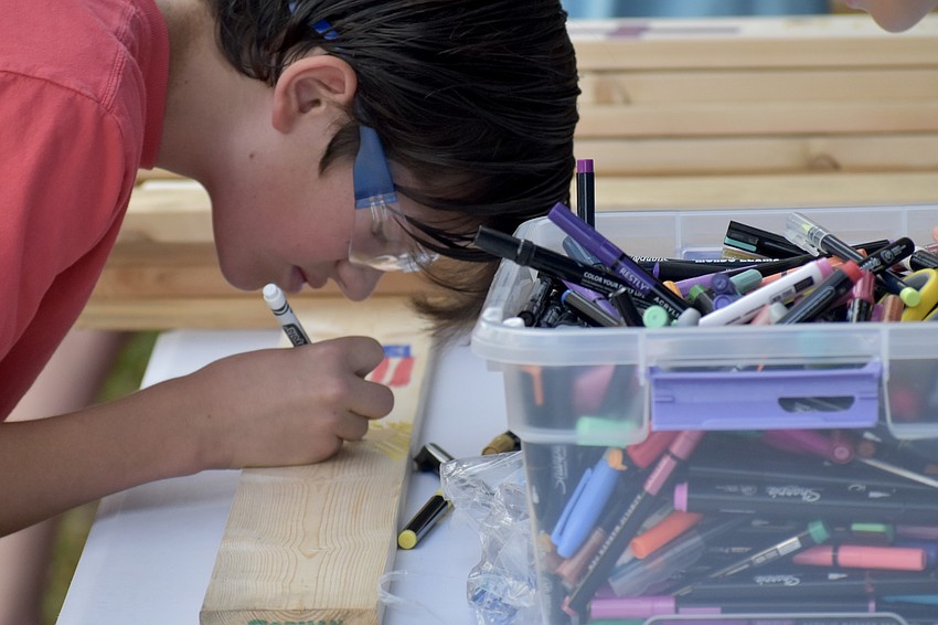 Walker Gaddy, 14, decorates the wood.