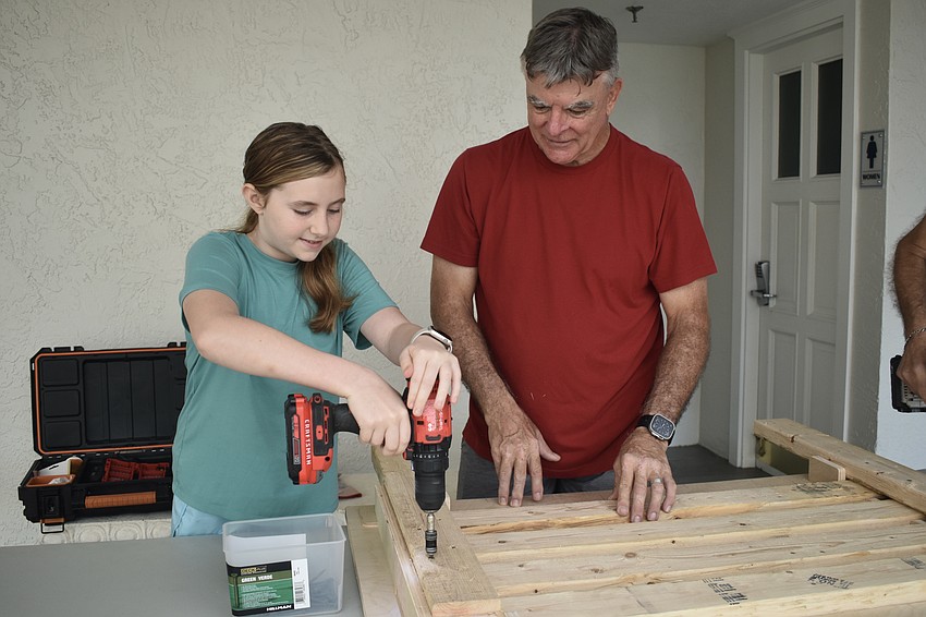 Claire Bragg, 11, learns from Bill Brush about using the drill.