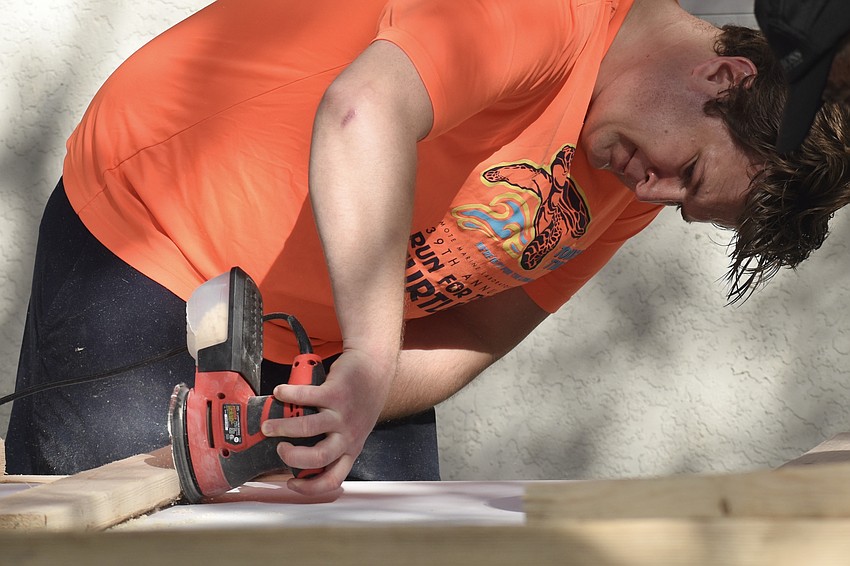 Adam Bragg sands down the wood.