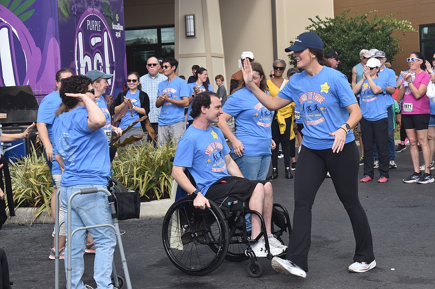 Emily Fenton and Liz Raedeke launch into a high five after a dance performance during the Stride to Thrive 5K event.