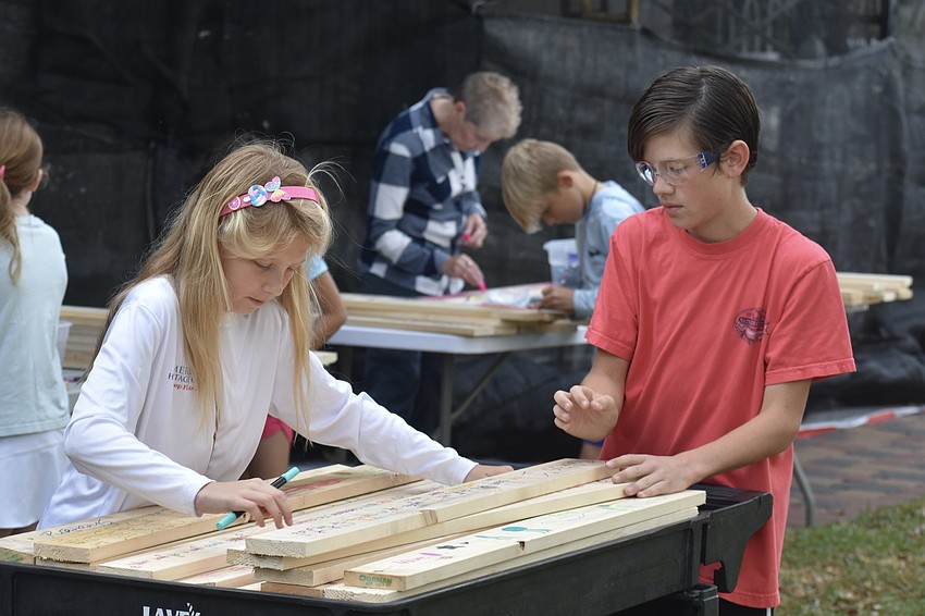 Magnolia Riner, 10 and Walker Gaddy, 14, set down pieces they have finished decorating and inscribing with Bible verses.
