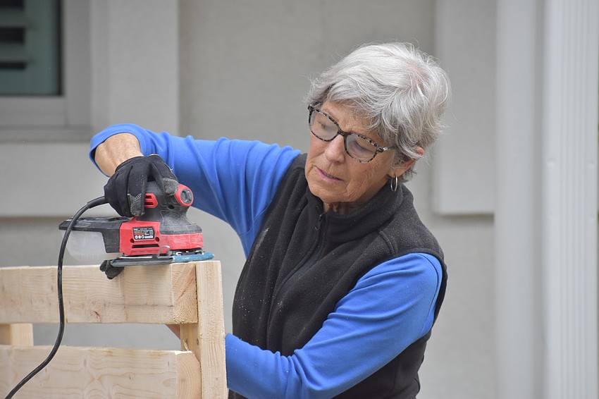 Lavonne Shedivy sands a series of boards.