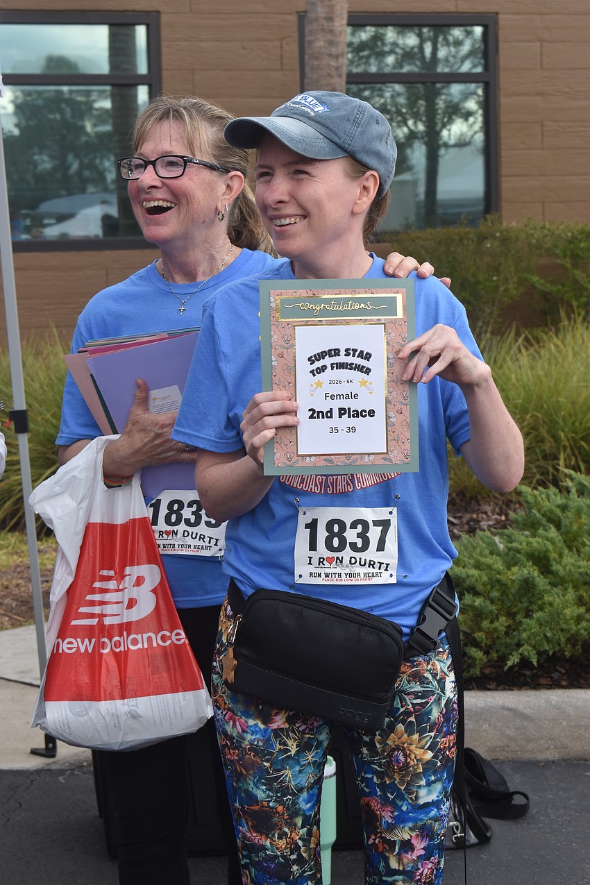 Julie Audet, a board member at Suncoast Stars Community, gives her daughter, Jenny, an award for placing second in her age group for the Suncoast Stars Community's Stride to Thrive 5K.