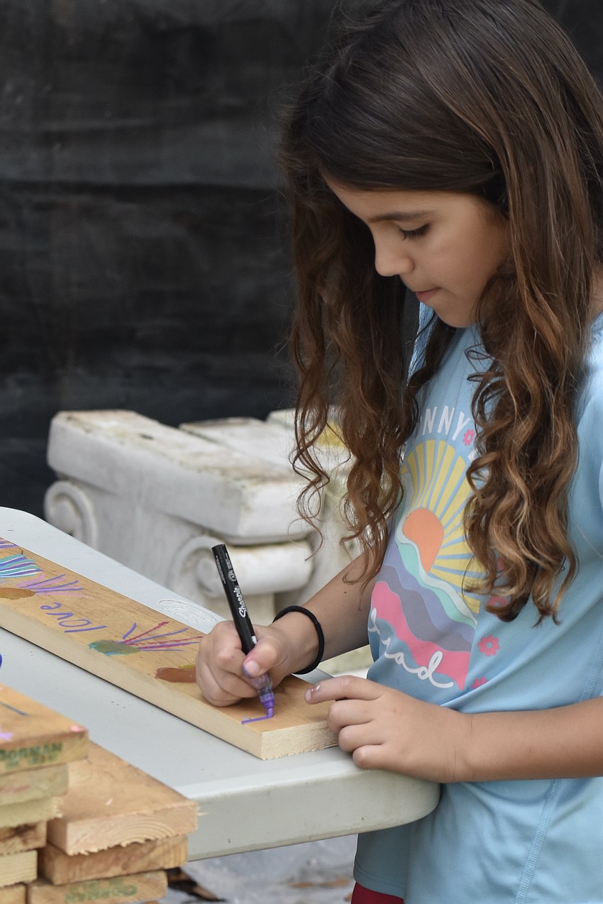 Julia Bragg, 7, decorates the wood.