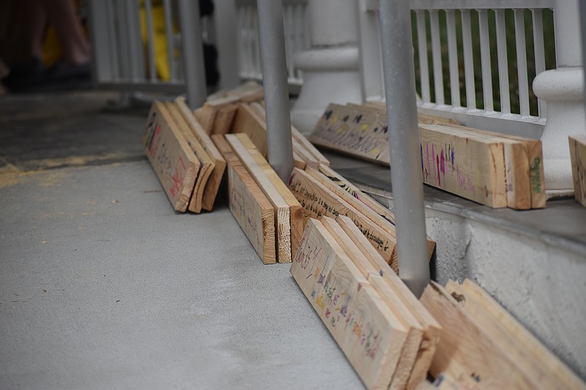 Boards with Bible verses and designs added by the kids are stacked for distribution.