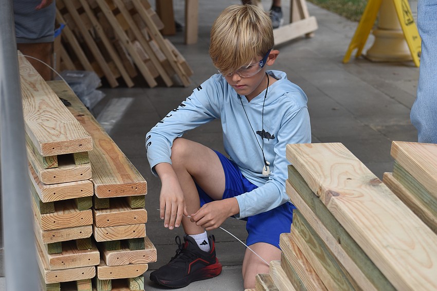Rhodes Riner, 8, ties a stack of boards together.