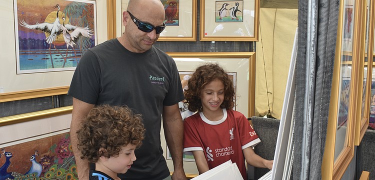 Gideon Demetrious, 6, Hani Demetrious and Jude Demetrious, 10, look through a series of prints.