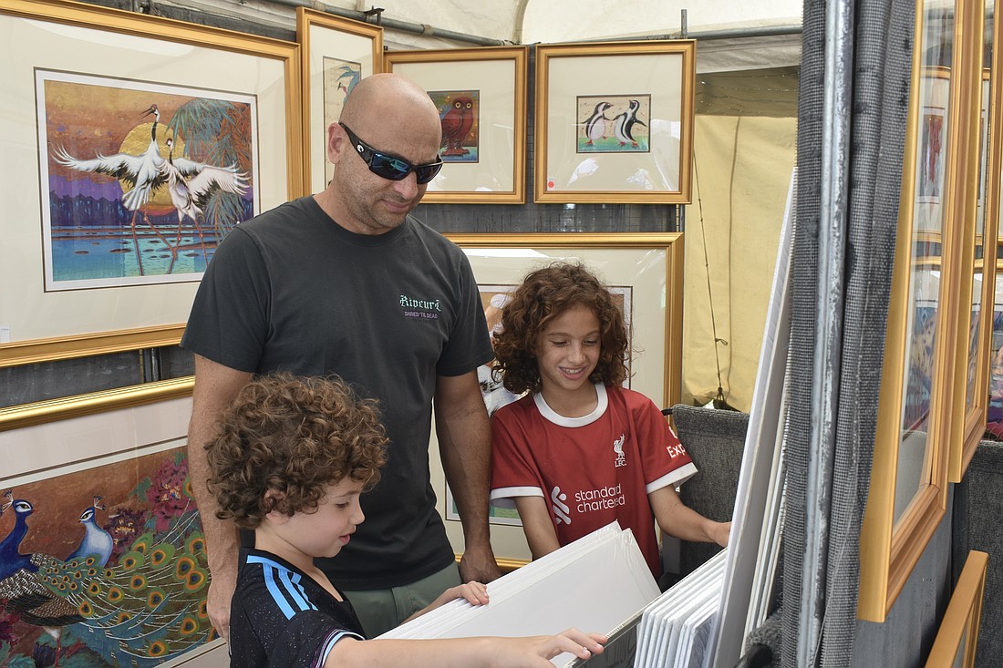 Gideon Demetrious, 6, Hani Demetrious and Jude Demetrious, 10, look through a series of prints.