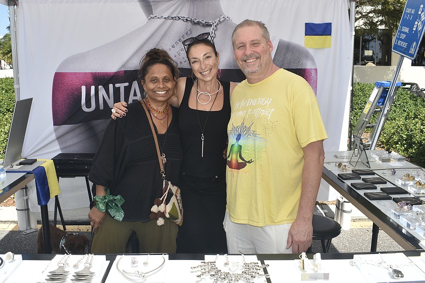 Disha Webb, Julia Bernadsky, and Jonathan Pittman stand in the booth of Untamed Hearts, a jewelry company that Bernadsky, a Sarasota resident, founded to support Ukraine, her native country.