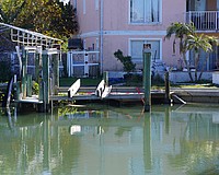 A boat is attached by a red strap to land as it lies under a dock in disrepair in a canal off General Harris Street. Longboat Key Fire Department determined the vessel is not leaking fuel.