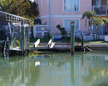 A boat is attached by a red strap to land as it lies under a dock in disrepair in a canal off General Harris Street. Longboat Key Fire Department determined the vessel is not leaking fuel.