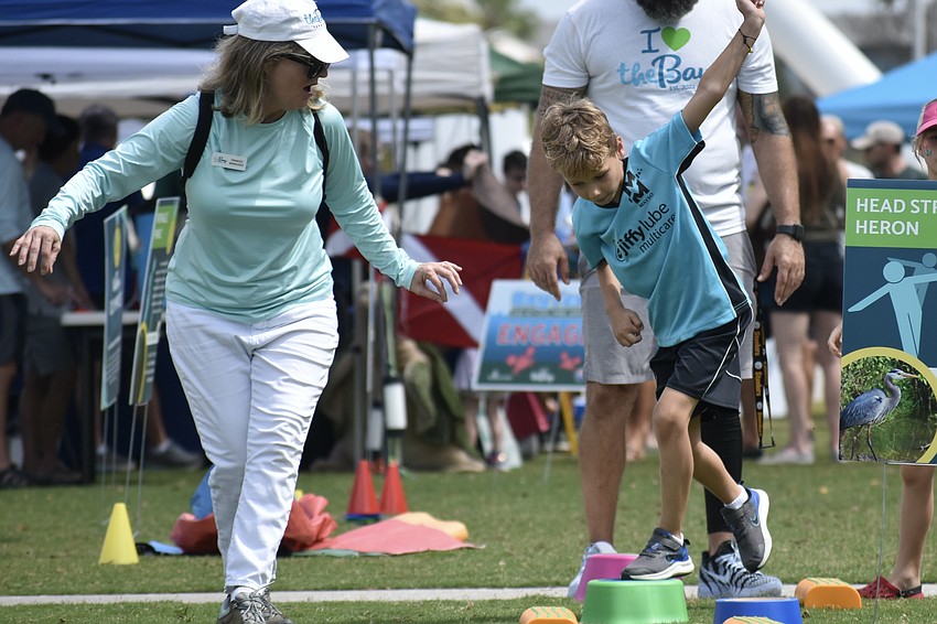 Frances Bermudez, activation and programming manager at The Bay, leads Brooks Bilbrey, 6, across a fitness course.