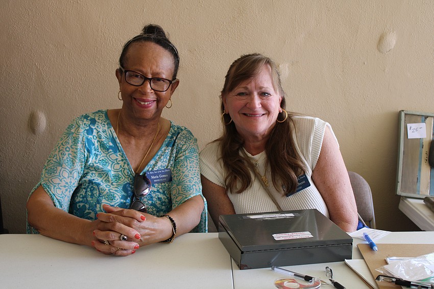 Maria Gomes and Maggie Oberst volunteer at the art section checkout table.