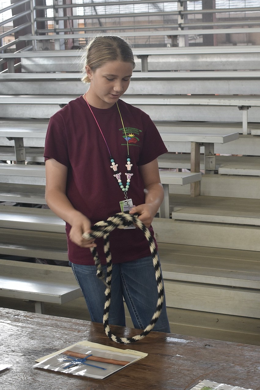 Lydia Egolf, a fifth grader in Youth Leaders in Production Agriculture, practices tying skills during an activity simulating different skills.