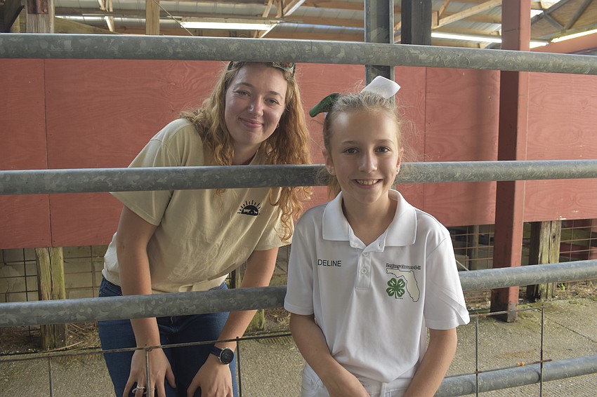 Kelsea Adams, an event helper, stands with fourth grader Adeline Earl of 4-H, as they prepare for a goat showing.