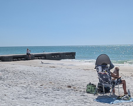 Beachgoers set up near and rest on one of two concrete permeable adjustable groins on the north end of Longboat Key.
