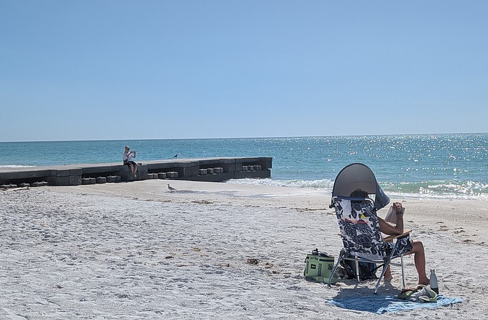 Beachgoers set up near and rest on one of two concrete permeable adjustable groins on the north end of Longboat Key.