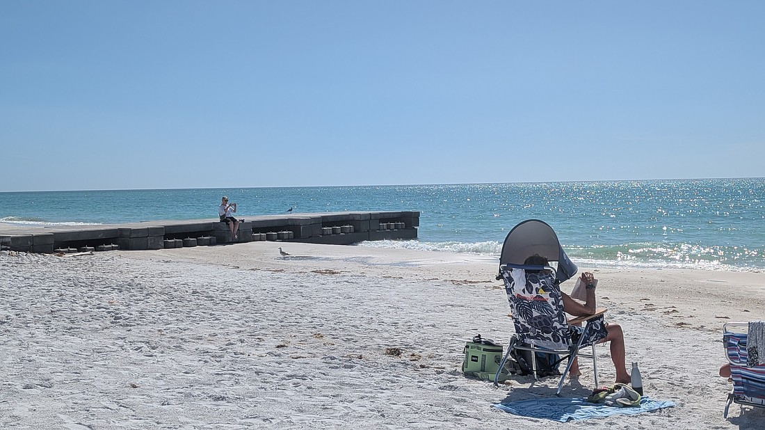 Beachgoers set up near and rest on one of two concrete permeable adjustable groins on the north end of Longboat Key.