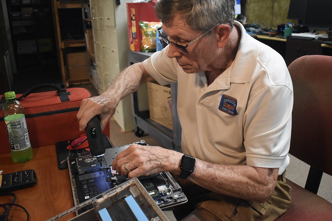 Mike Hutchinson repairs a laptop.