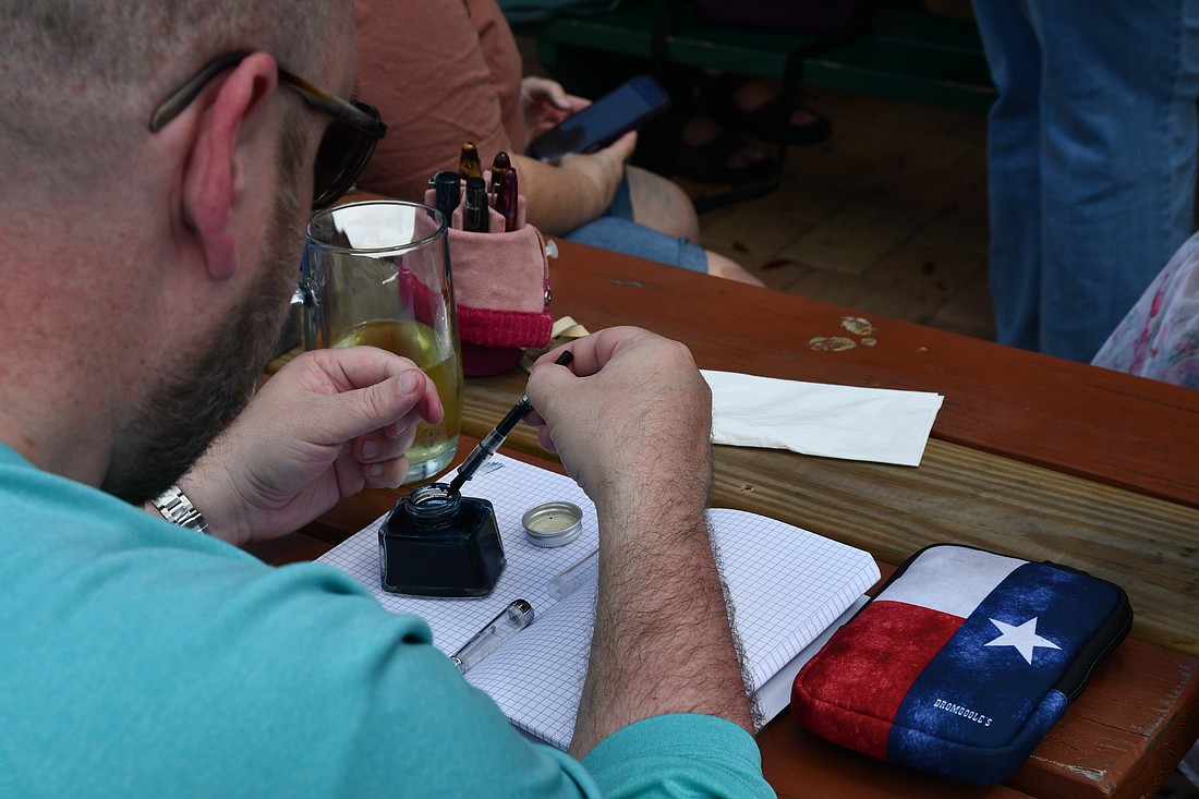 A member of the Orlando Pen Club refills a fountain pen for another club member.